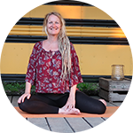 Debby Kluyskens-Zonneveld zittend op de grond voor een schoolbus