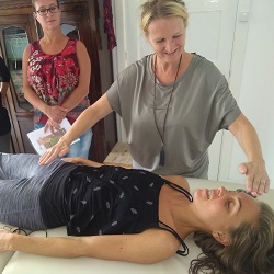 Handen die reiki geven in de nek van persoon die op een behandeltafel ligt